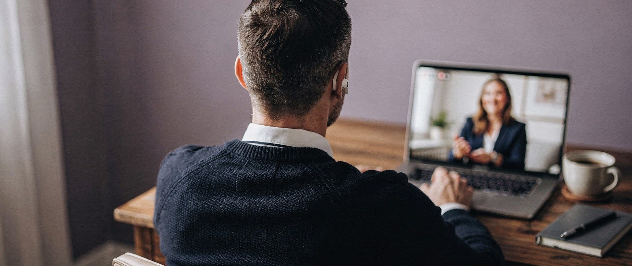 Ein Teilnehmer sitzt zuhause am Schreibtisch und nimmt mit Laptop und AirPods an einer Online-Session teil